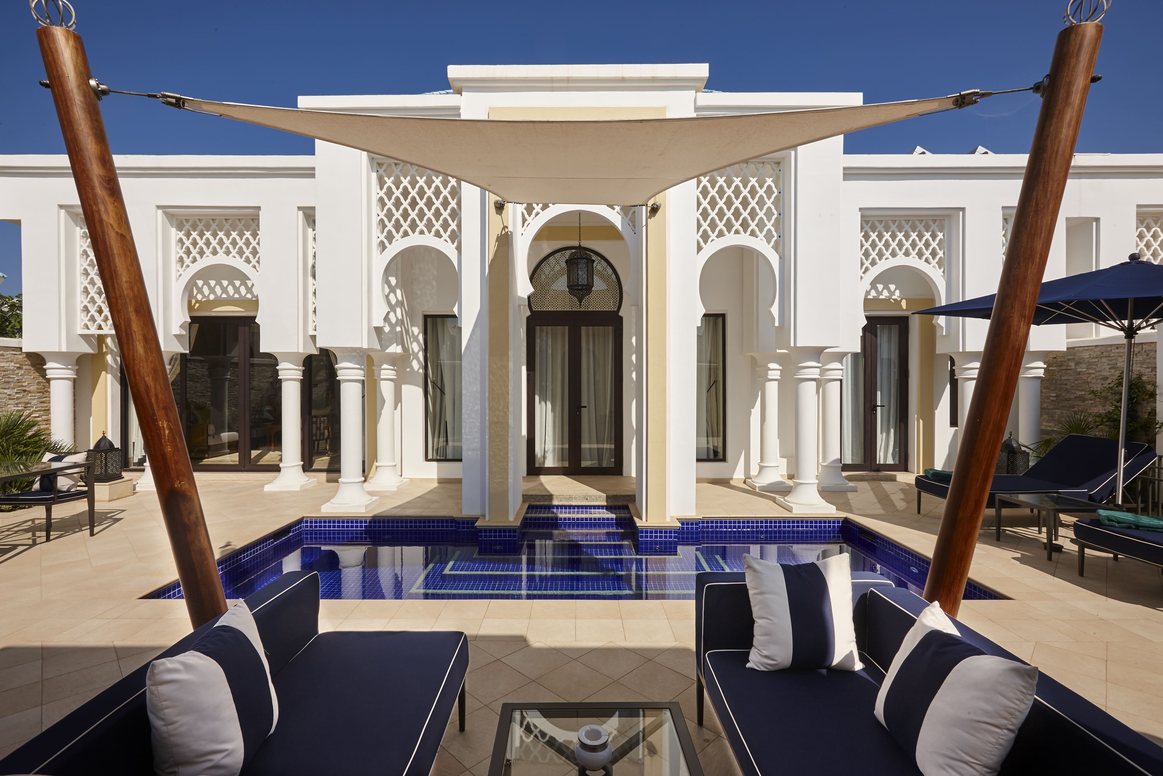 Poolside lounge area with white columns at Banyan Tree Tamouda Bay Harmony Pool Villa, framed by modern pergola.